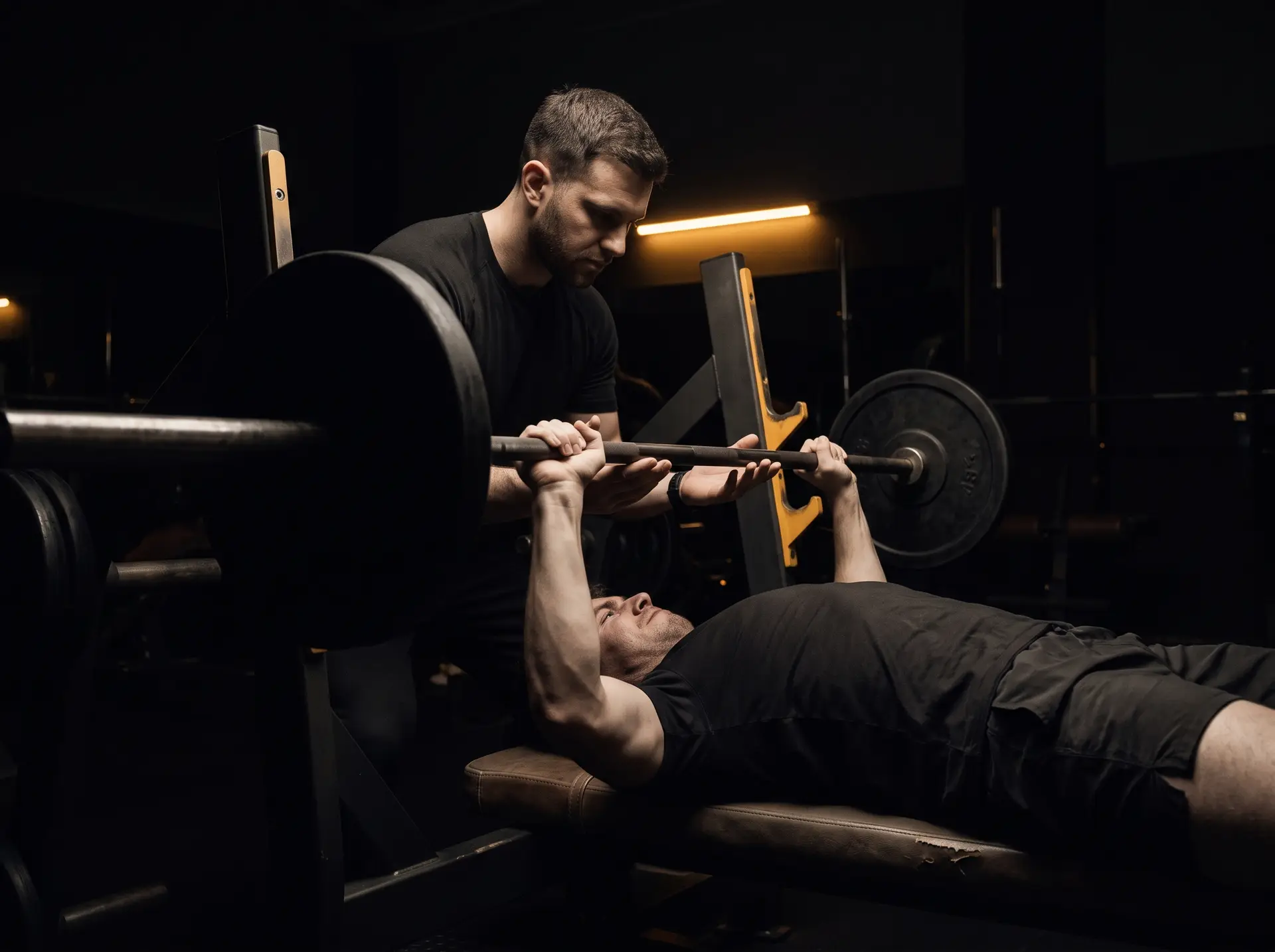 A trainer spotting a client on a bench press